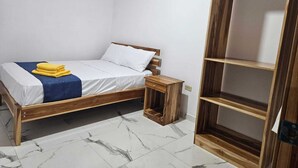 Een slaapkamer met een houten bed, een nachtkastje, een kledingkast en een marmeren vloer.