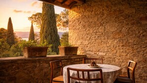 A stone wall, a round table with chairs, and potted plants. - Scappo in Umbria, Villa Maria (Panicale)