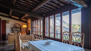 A dining area with a table set for four, surrounded by chairs, a lamp, and a bookshelf. - Scappo in Umbria, Villa Maria (Panicale)