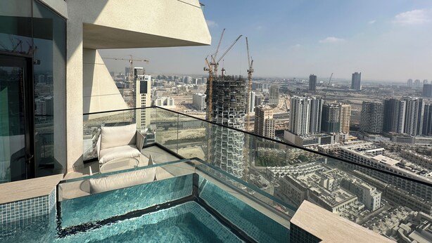 Una piscina en la azotea con barandilla de cristal, diseño arquitectónico moderno y vistas a la ciudad.