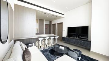 Una sala de estar moderna con un sofá, una mesa de centro, un televisor y una zona de bar.