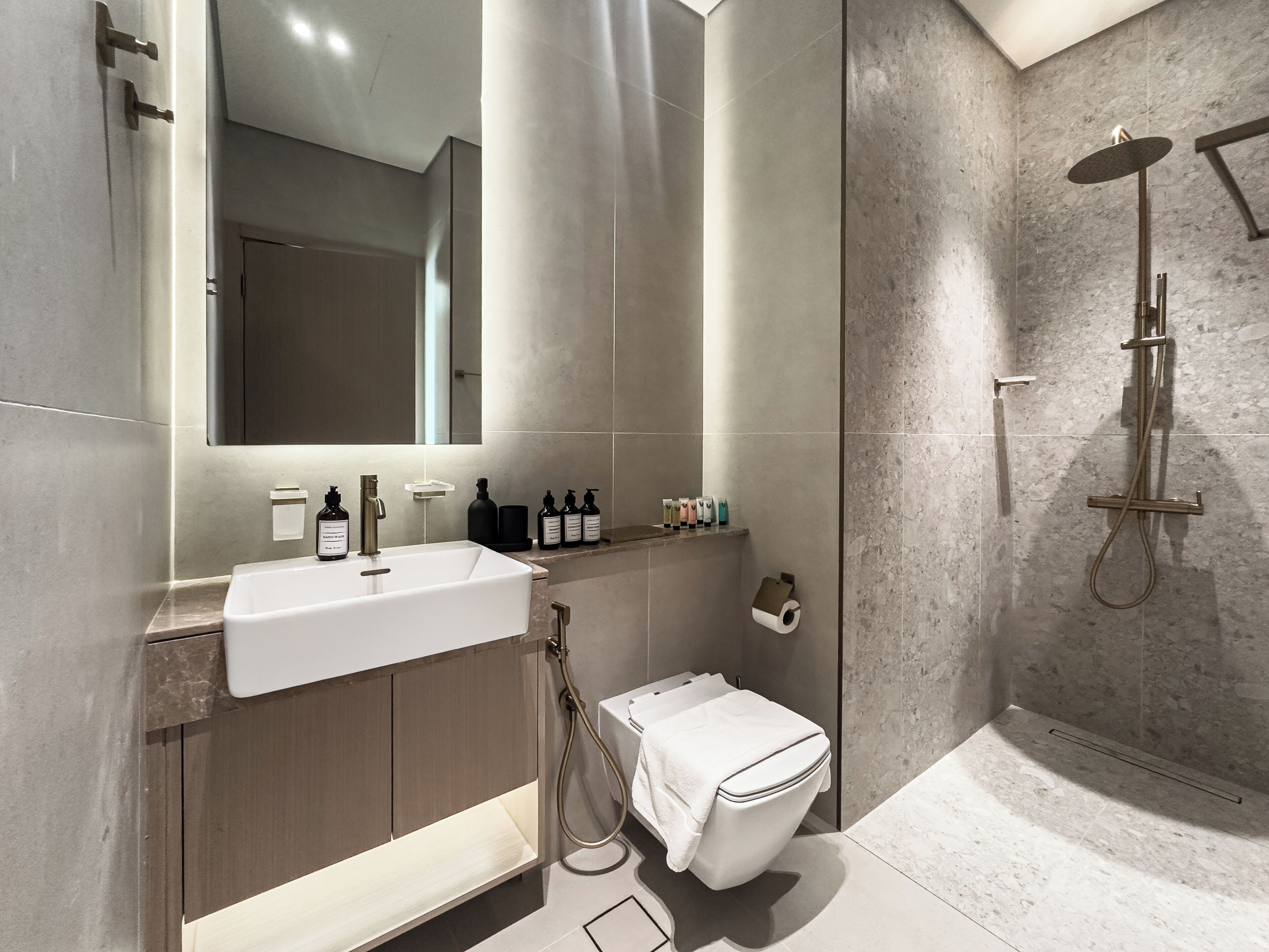 A modern bathroom with a large mirror, a sink, a toilet, and a shower area.