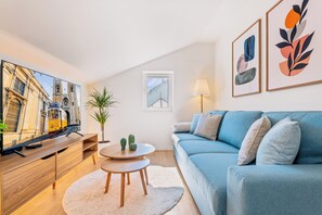 Una sala de estar moderna con televisor, sofá, mesa de centro y obras de arte.