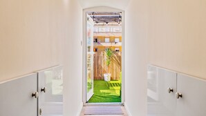 A hallway leading to a room with a wooden ceiling, a small potted plant, and a view of a fenced outdoor area. - Rooftop Apartment with Private Terrace (Lisboa)