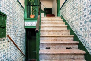 Una escalera con barandas verdes y paredes decoradas.