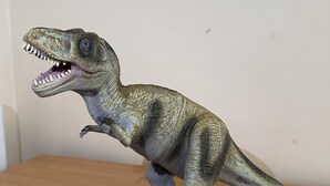Ein Dinosaurier-Modell auf einer Holzoberfläche.