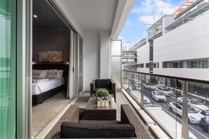 Ein Balkon mit Bett, Sitzecke und Blick auf einen Parkplatz.