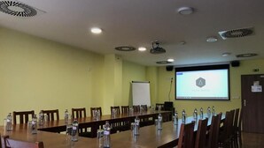 A conference room with a long table, chairs, a projector screen, and a whiteboard. - Hotel Aréna (Brumov-Bylnice)