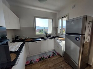 A modern kitchen with white cabinets, a stainless steel refrigerator, and a window with a view of the outdoors. - Apartment in the center, bright and modern style in Villasimius (Villasimius)