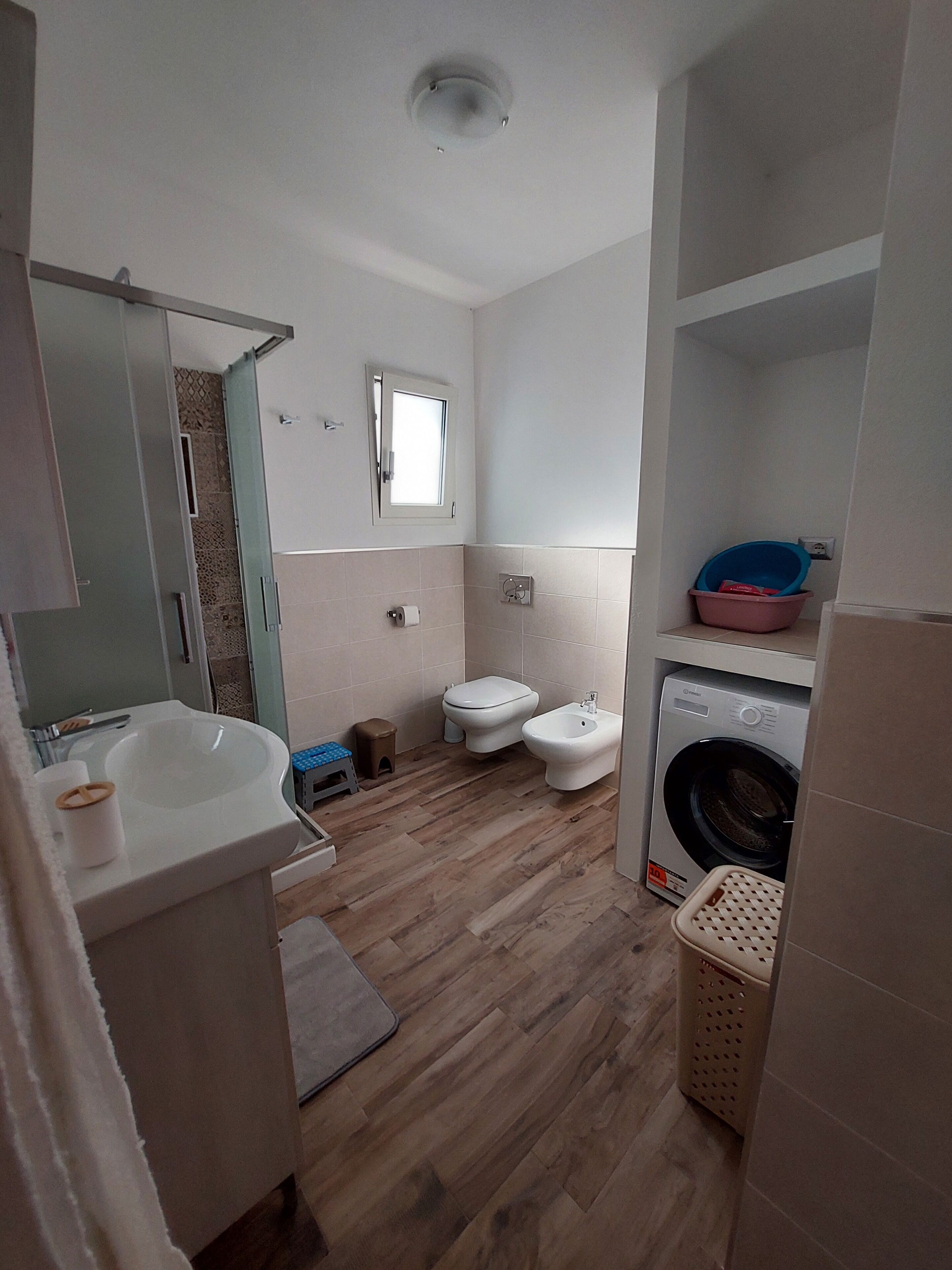 Un bagno con lavandino, WC, bidet e lavatrice.