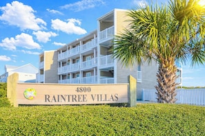 Un edificio a più piani con balconi, con la scritta 'RAINTREE VILLAS' all'ingresso.