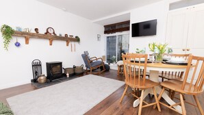 A cozy living room with a fireplace, wooden furniture, and a TV mounted on the wall.