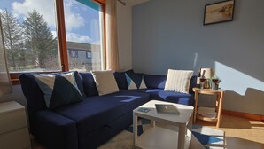 A modern living room with a dark blue sofa, a white coffee table, and a small side table with a lamp.