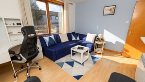A modern living room with a blue sofa, a white coffee table, and a black office chair.