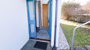 A blue-framed entrance to a building with a door, a small step, and a metal handrail.
