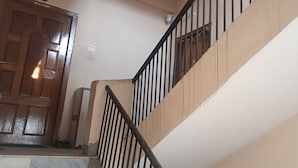A staircase with a wooden handrail and a metal banister, leading to a door labeled 'DR. R. R. PANDIT.' - KK HOMES GUWAHATI (Guwahati)