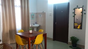 A small dining area with a wooden table and yellow chairs, a sink, and a mirror on the wall. - KK HOMES GUWAHATI (Guwahati)