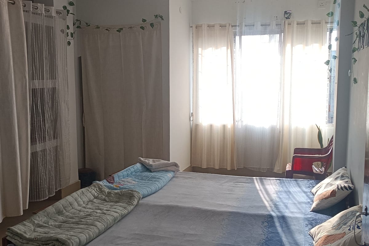 A room with a bed, a chair, and a window with curtains.