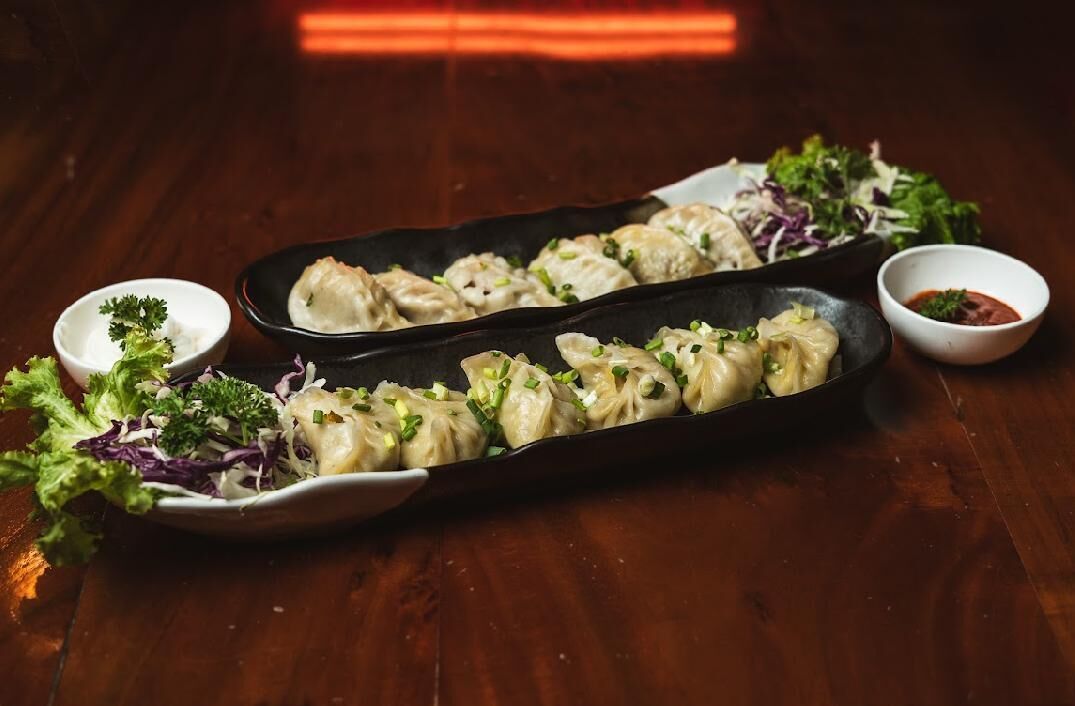 Uma travessa de pasteis com uma salada e dois pequenos recipientes de molho.