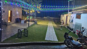 An outdoor area with a paved walkway, seating, and a motorcycle. - Natures Crown Resort (Dehradun)