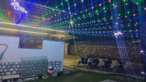 A building with a stone wall, a glass enclosure, and several motorcycles parked outside. - Natures Crown Resort (Dehradun)