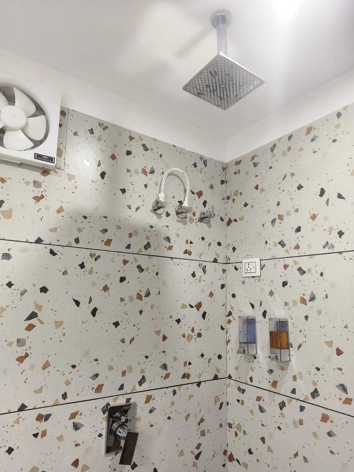 A bathroom with a shower, a fan, and a hand dryer.