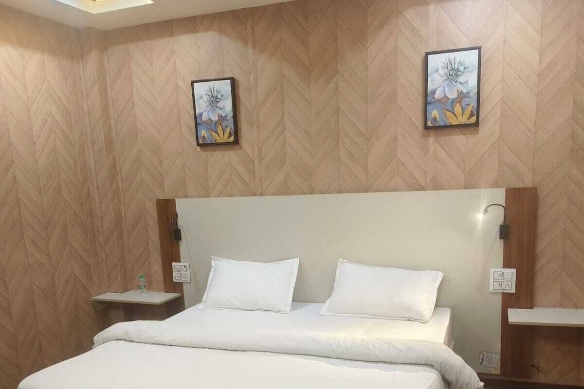 Een hotelkamer met een groot bed, houten vloeren, een modern hoofdeinde en twee kunstwerken aan de muur.