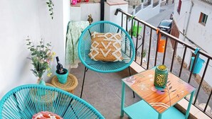 Een balkon met turquoise stoelen, een klein tafeltje en een decoratieve lantaarn.