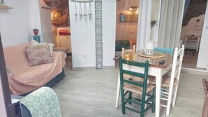Een gezellige zithoek met een bank, een eettafel met stoelen en een trap naar een andere kamer.