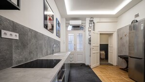 A modern kitchen with a black countertop, a stainless steel refrigerator, and a double sink. - AVATAR Suite (Budapest)