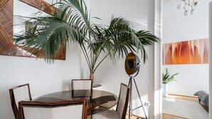 A dining area with a round table, chairs, a potted plant, and artwork on the walls. - AVATAR Suite (Budapest)
