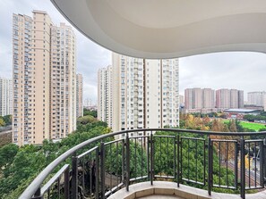Un palazzo residenziale a più piani con numerosi balconi, una ringhiera curva e vista su edifici circostanti e aree verdi.