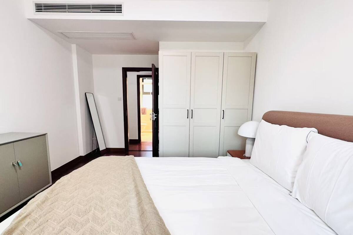 Una habitación de hotel con cama, armario, escritorio y puerta que da a otra habitación.