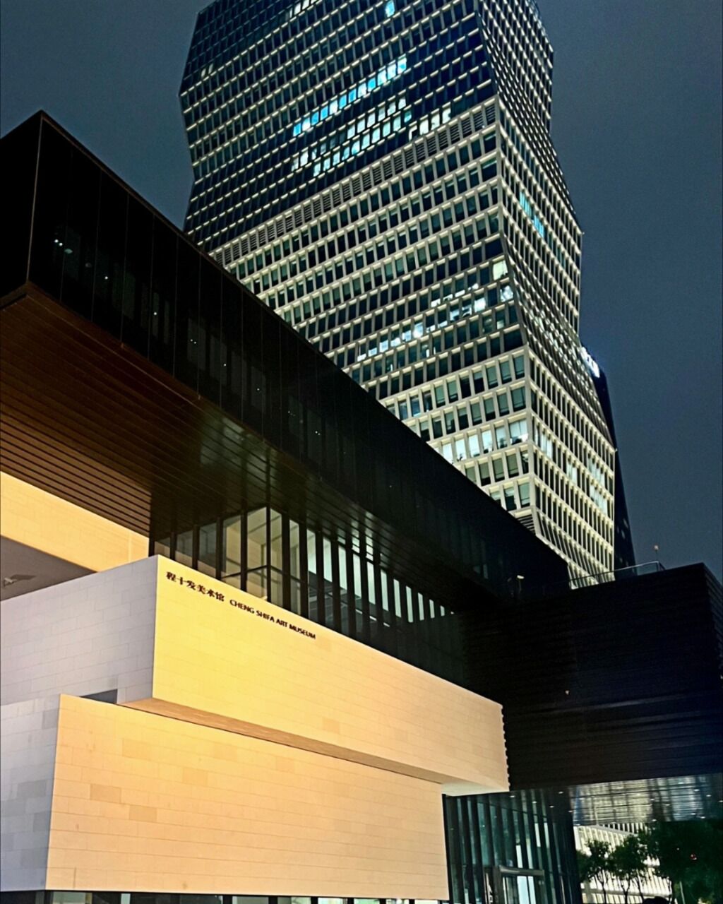 A modern building with a glass facade and illuminated windows at night.