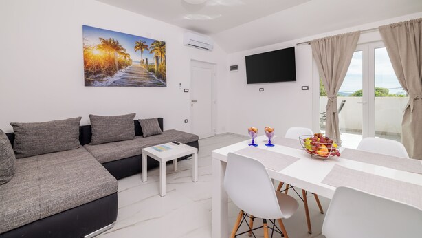 Ein modernes Wohnzimmer mit einer Couch, einem Esstisch und einem Fernseher.