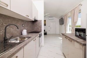 A modern kitchen with a marble countertop, stainless steel sink, and a flat-screen TV. - Charming vacation apartment with swimming pool, barbecue & private parking space (Kras)