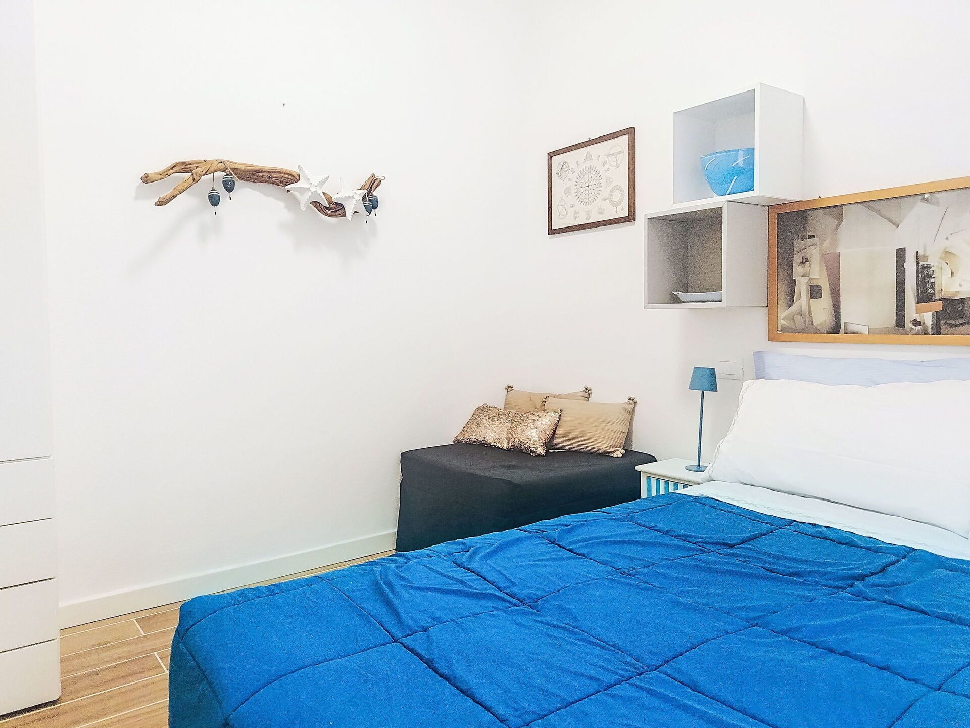 Een slaapkamer met een bed, nachtkastje, stoel, bureau, spiegel en decoratie aan de muur.