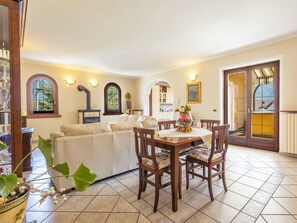 A dining area with a table and chairs, a sofa, a fireplace, and a view of the outside. - Cosy apartment for 5 guests with WIFI, TV and terrace (Premosello-chiovenda)