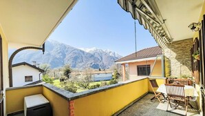 Ein Balkon mit Bergblick, ein Tisch mit Stühlen und ein Grill.