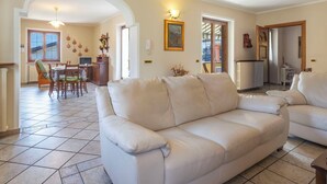 Ein Wohnzimmer mit einer Couch, einem Essbereich mit Stühlen, einem Tisch und einer Küchenzeile mit Heizkörper.