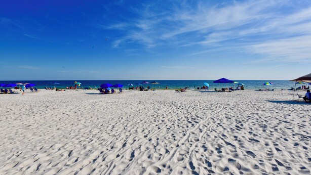 Una playa con arena blanca y cielo azul despejado.