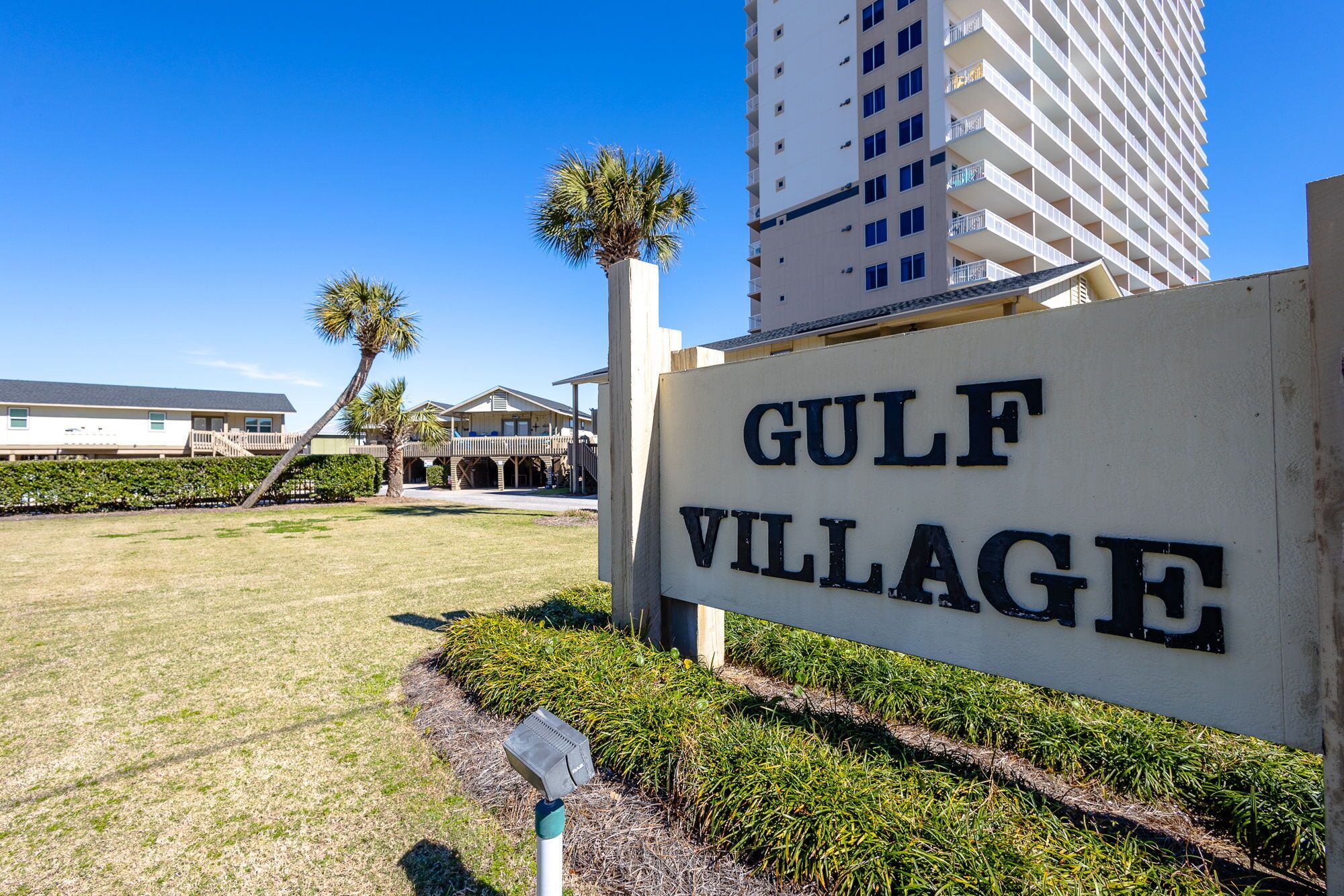 Skilt for Gulf Village med en bygning i baggrunden.