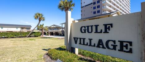 Skilt for Gulf Village med en bygning i baggrunden.