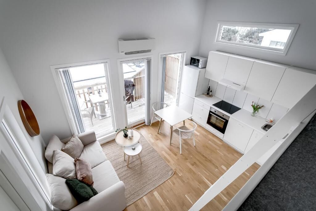 A modern kitchen with white cabinetry, a dining area with a white table and chairs, and a living area with a sofa and a coffee table.