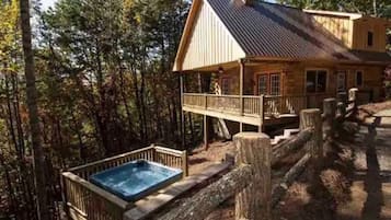 A wooden cabin with a balcony and a hot tub.