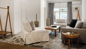 A living room with a sofa, a coffee table, a wooden stand, and a view of the outside. - Patron 1 Pool Sunset Villa- Seven Bedrooms (Mikonos)