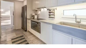 A modern kitchen with white cabinets, stainless steel appliances, a built-in oven, and a large window. - Patron 1 Pool Sunset Villa- Seven Bedrooms (Mikonos)