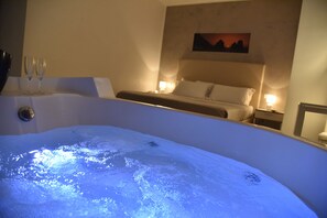 Une chambre avec une baignoire, un lit et deux tables de chevet avec des lampes.