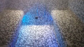 A steam room with a tiled floor and benches, illuminated by overhead lights. - Favorite Room&Spa (San Giuseppe Vesuviano)