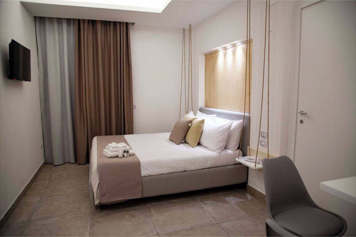 A neatly arranged hotel room with a bed, a chair, a desk, and a TV.
